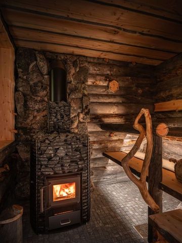Holzsauna mit Steinofen, Holzwänden und Kerzenlicht in der Ultra Lodge