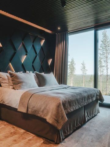Suite der Villa mit Doppelbett, beleuchteter Wandverkleidung und Fenster zum Wald