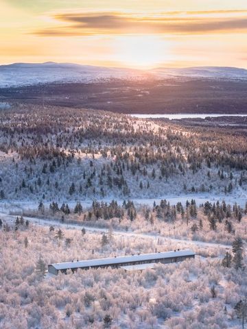 Blick über verschneites Fjell und Wälder bei Sonnenuntergang in Finnisch-Lappland