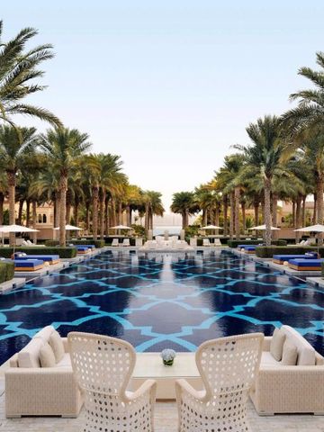 Langer, luxuriöser Pool mit Palmen und eleganten Sitzbereichen