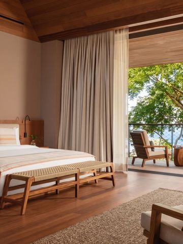 Luxuriöses Schlafzimmer mit Holzinterieur und Balkon mit Meerblick.