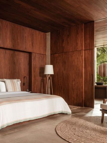 Luxuriöses Schlafzimmer mit Holzverkleidung und bodenlangen Fenstern mit Gartenblick