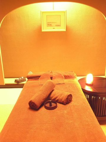 Angenehm beleuchteter Spa-Behandlungsraum mit Handtüchern und entspannender Atmosphäre