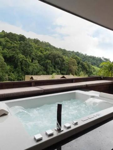 Privater Whirlpool auf Terrasse mit Blick auf üppigen Wald.