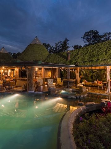 Außenansicht der Lodge bei Nacht mit Beleuchtung und Pool
