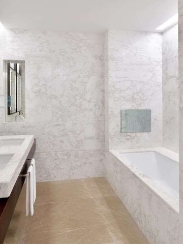 Moderner Badezimmerbereich mit Marmordekor und großer Badewanne