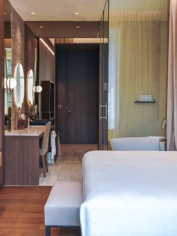 Elegantes Zimmer mit Holzoptik und offenem Badbereich.