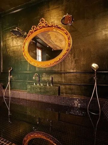 Luxuriöses Badezimmer mit goldener Wandverkleidung und ovalem Spiegel