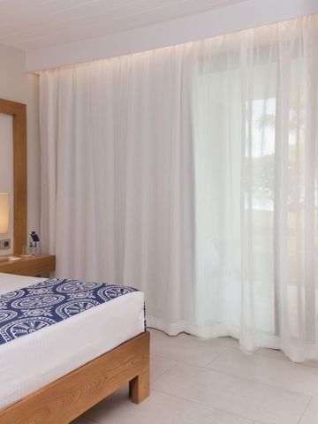 Schlichtes Hotelzimmer mit großen Fenstern und Gartenblick
