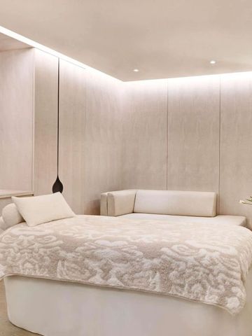 Helles Spa-Zimmer mit Massageliege und dezenter Beleuchtung
