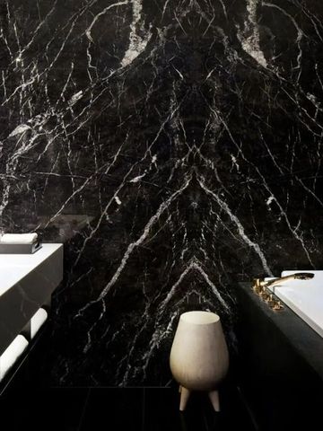 Luxuriöser Badezimmerbereich mit dunklem Marmor und stilvollen Armaturen.