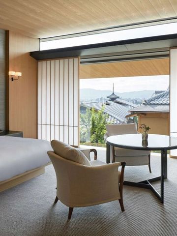 Hotelzimmer mit großem Bett, eleganten Sesseln und Aussicht auf traditionelle Architektur