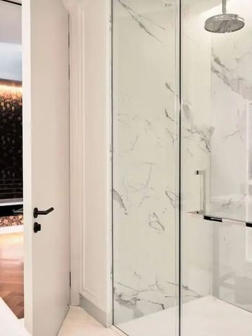 Luxuriöses Badezimmer mit Marmor-Duschwand und Glasdusche