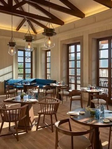 Lichtdurchflutetes Restaurant mit stilvollen Holzmöbeln im Cap Vermell Grand Hotel