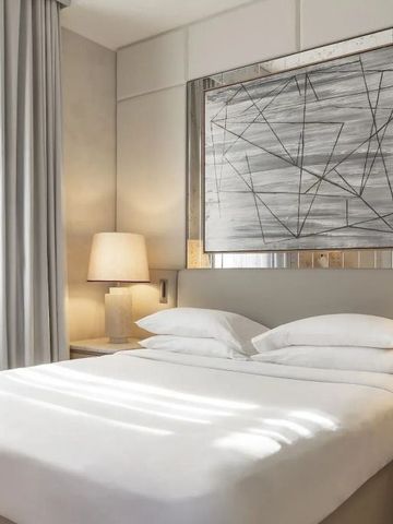 Modernes Hotelzimmer mit Kunstwerk über dem Bett und sanfter Beleuchtung
