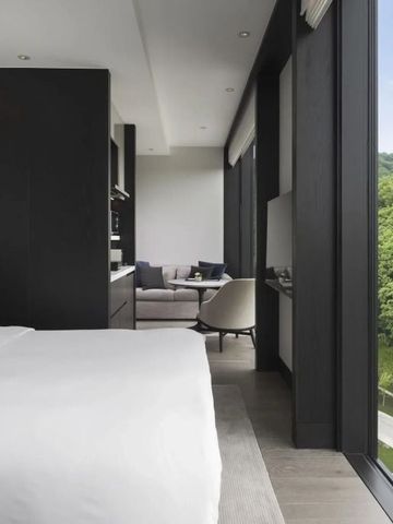 Elegant eingerichtetes Hotelzimmer mit großem Fenster und grünem Ausblick.