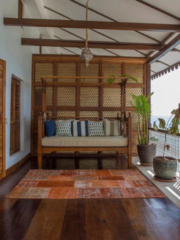Balkon mit traditionellem Sofa und exotischen Pflanzen mit Meerblick
