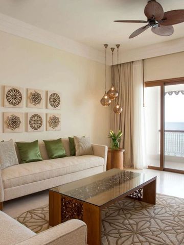Stilvolles Wohnzimmer mit Sofas und Glaswand mit Balkonblick auf das Meer