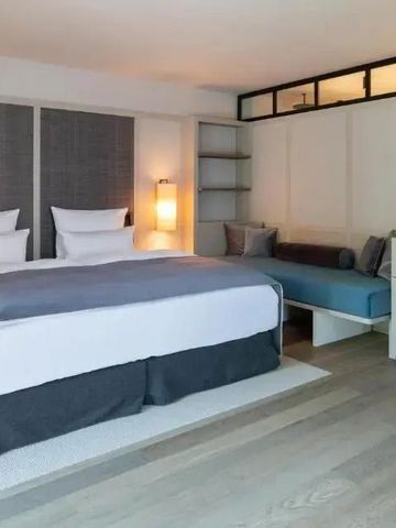 Geräumiges Hotelzimmer mit Doppelbett, modernem Dekor und bequemer Sitzecke.