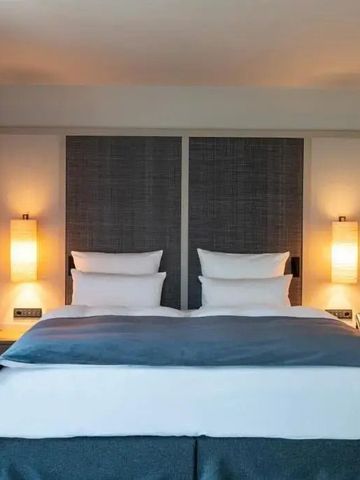 Komfortables Hotelzimmer mit Doppelbett in schlichter, eleganter Einrichtung.