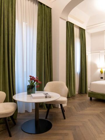 Stilvolles Hotelzimmer mit Grünakzenten und Sitzbereich im Patria Palace Hotel Lecce.