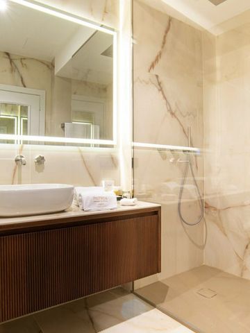 Elegantes Badezimmer mit moderner Glasdusche und Marmorverkleidung