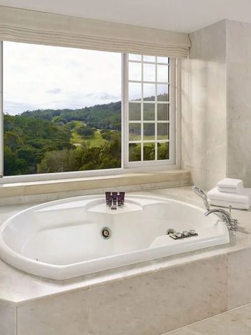 Große Badewanne mit Panoramafenster und Blick auf grüne Landschaft