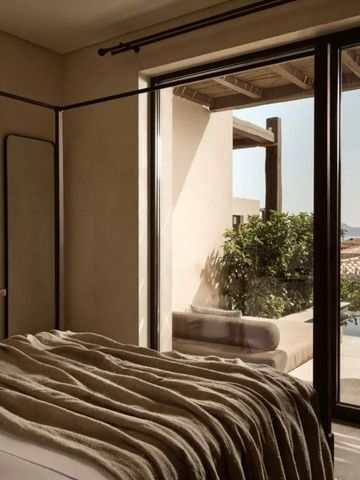 Schlafzimmer mit großen Fenstern und Blick auf grüne Landschaft