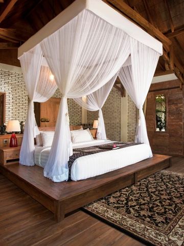 Luxus-Schlafzimmer im tropischen Stil mit Baldachinbett und Holzboden