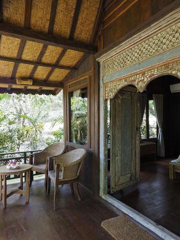 Veranda mit Sitzgelegenheit und Blick in den tropischen Garten