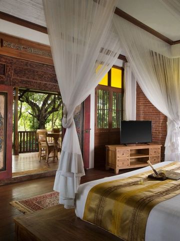 Charmantes Zimmer mit Himmelbett und Blick auf eine private Veranda mit Garten.