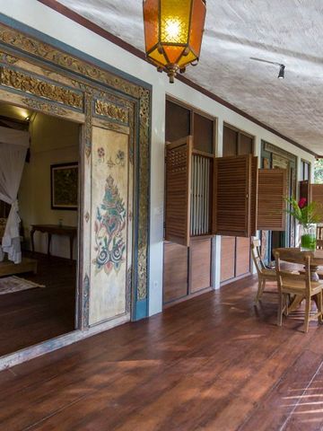 Veranda mit Holzboden und kunstvoll verzierten Türen und gemütlichem Sitzbereich