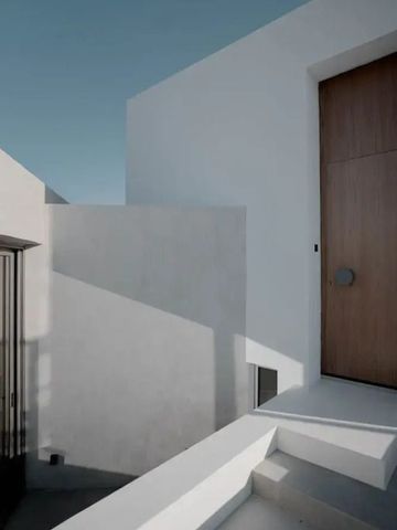 Minimalistischer Hoteleingang mit großer Holztür und weißen Wänden