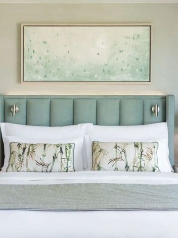 Elegantes Hotelzimmer mit gepolstertem Kopfteil und Kunstwerk