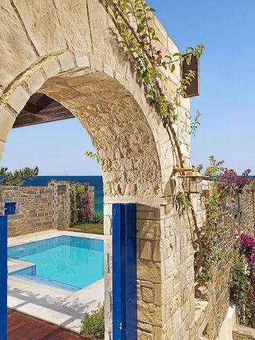 Meerblick durch einen Steinbogen auf einen privaten Pool mit blühenden Pflanzen.
