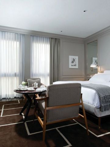 Helles Hotelzimmer mit großen Fenstern und einem komfortablen Bett