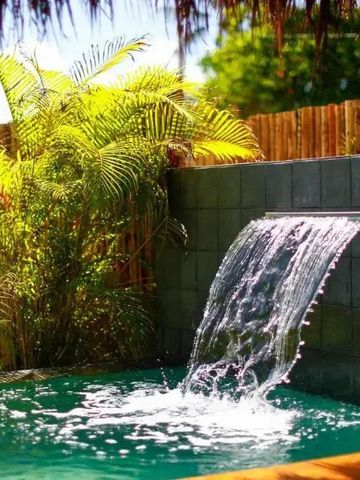 Kleiner Pool mit Wasserfall und tropischen Pflanzen