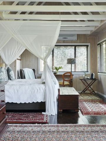 Schlafzimmer mit Baldachinbett und Holzbalkendecke