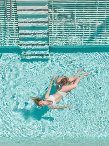 Frau entspannt schwimmend im klaren, türkisen Pool