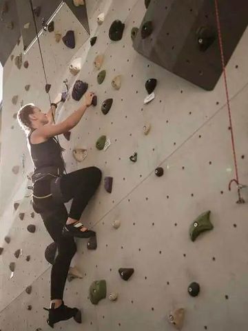 Person klettert an einer Outdoor-Kletterwand bei Sonnenlicht