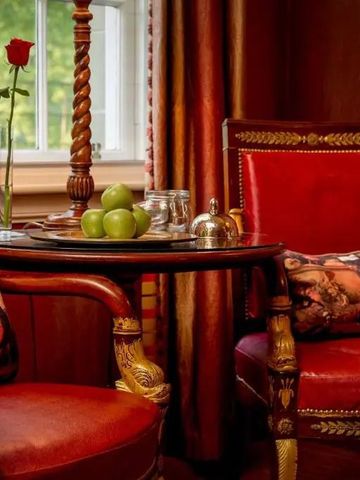 Rote Ledersessel und Tisch mit grünen Äpfeln in gemütlichem Raum mit großem Fenster