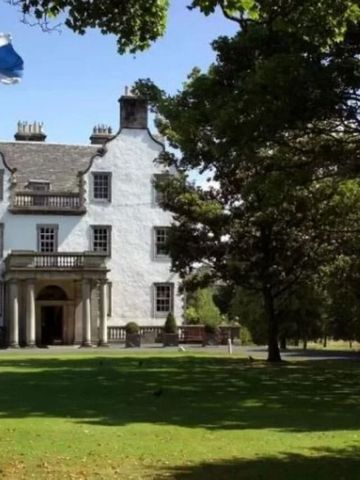 Historisches Gebäude von Prestonfield House umgeben von Bäumen und Rasen.