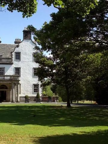 Vorderansicht von Prestonfield House mit schottischer Flagge und Garten.