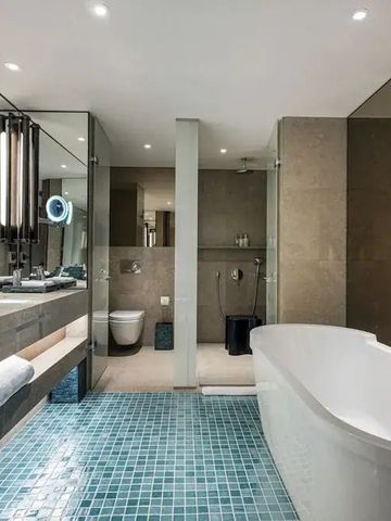 Geräumiges Badezimmer mit freistehender Badewanne und gläserner Duschwand