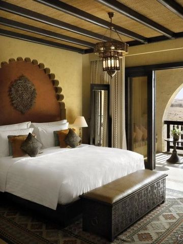 Luxuriöses Hotelzimmer mit großem Bett und Blick auf die Wüstenlandschaft.