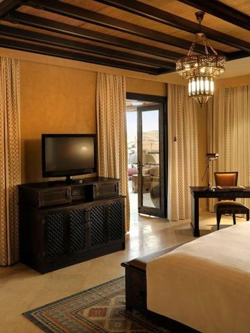 Luxuriöses Hotelzimmer mit warmen Farben, TV und Schreibtisch mit Wüstenblick.