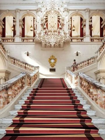 Große Treppe mit rotem Teppich und opulentem Kronleuchter