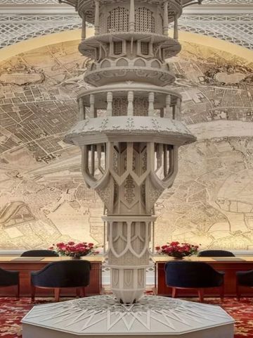 Elegante Lobby mit kunstvollem Säulendekor und roten Sitzmöbeln vor Wandkarte.