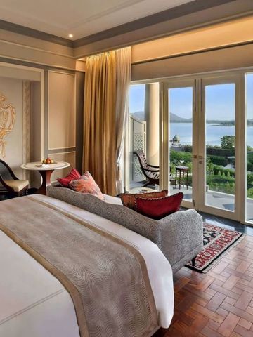 Suite mit großem Bett und Terrasse mit Seeblick im Hintergrund