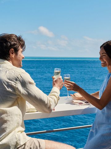 Paar stößt mit Sekt an der Barreling des Sonnendecks an, Blick über das Meer zum Horizont